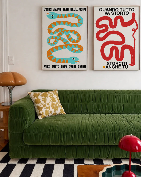 Poster artistici con illustrazioni grafiche appesi sopra divano verde in un soggiorno moderno